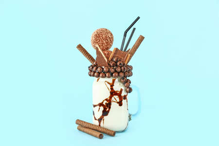 Mason jar with delicious freak shake on color background