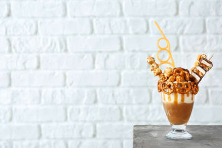 Delicious freak shake on table against white brick background