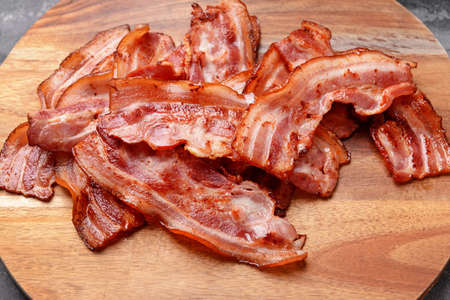 Fried bacon on wooden board, closeup