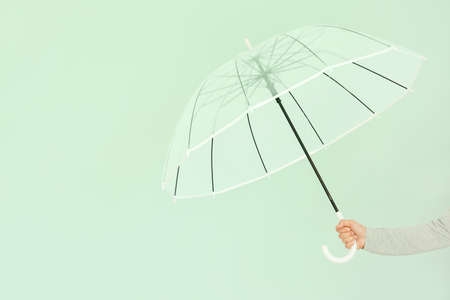 Female hand with stylish umbrella on color backgroundの写真素材