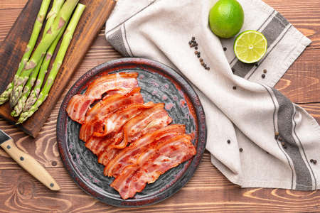 Plate with fried bacon on wooden tableの写真素材