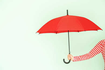 Female hand with stylish umbrella on color backgroundの写真素材