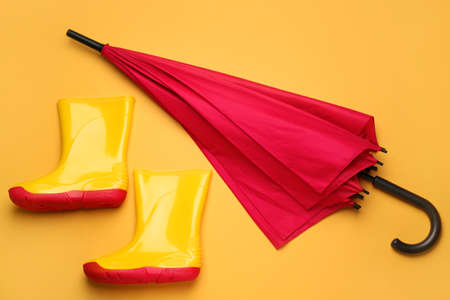 Stylish umbrella and gumboots on color backgroundの写真素材