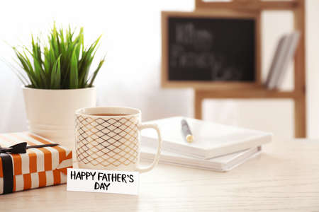 Cup of coffee, greeting card for Father's Day and gift on tableの写真素材