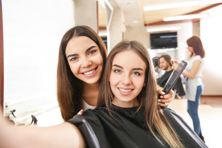 Young woman taking selfie with her hairdresser in salonの写真素材