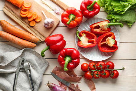 Ripe red peppers with other vegetables on tableの写真素材