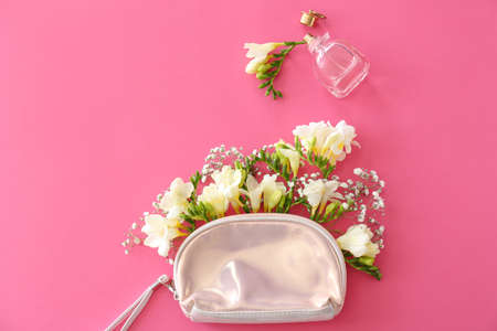 Cosmetic bag with beautiful freesia flowers and perfume on color backgroundの写真素材