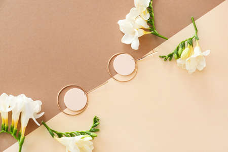 Earrings and beautiful freesia flowers on color backgroundの写真素材