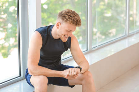 Sporty young man checking his pulse after training in gymの写真素材