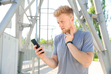 Sporty young man checking his pulse outdoors