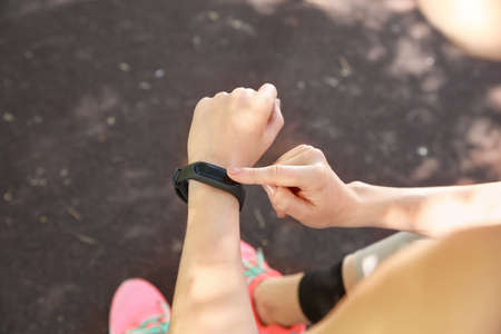 Sporty young woman checking her pulse outdoors, closeup