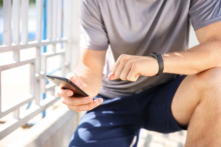Sporty young man checking his pulse outdoors
