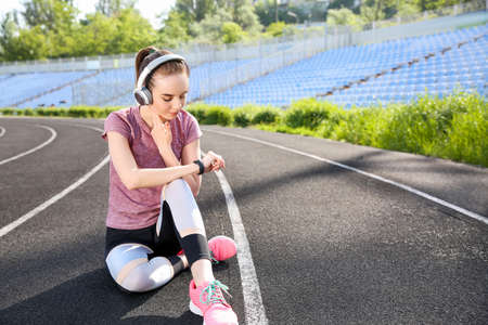 Sporty young woman checking her pulse at the stadium