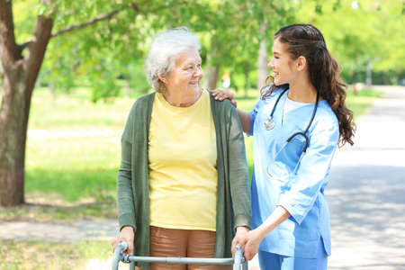 Caregiver walking with senior woman in parkの写真素材