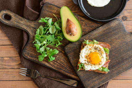 Tasty toast with bacon and fried egg on wooden table