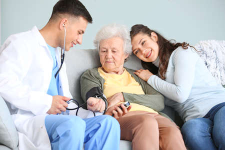 Doctor examining senior woman at home