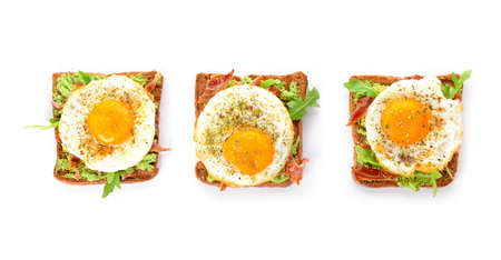 Tasty toasts with bacon and fried egg on white backgroundの写真素材