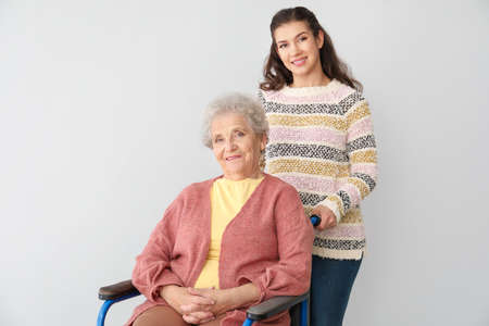 Happy woman with grandmother on gray background