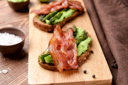 Tasty toasts with bacon on wooden boardの写真素材