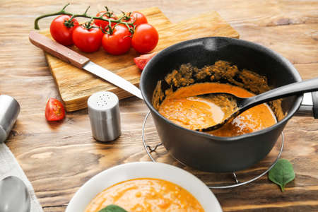 Saucepan with delicious cream soup on wooden tableの写真素材