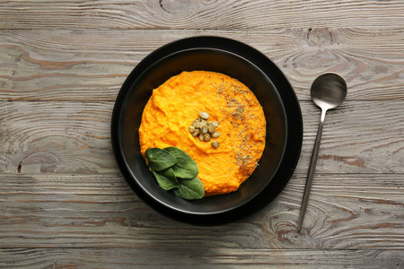 Bowl with delicious pumpkin cream soup on wooden tableの写真素材