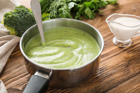 Saucepan with delicious broccoli cream soup on wooden tableの写真素材
