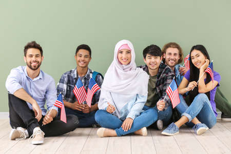 Group of students with USA flags sitting near color wallの写真素材