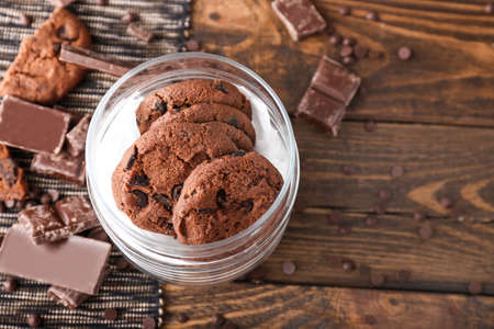 Glass jar with tasty chocolate cookies on wooden table