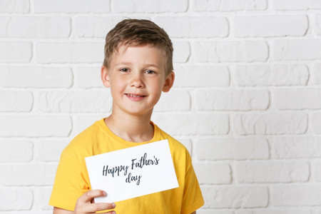 Little boy holding greeting card for Father's Day on white background