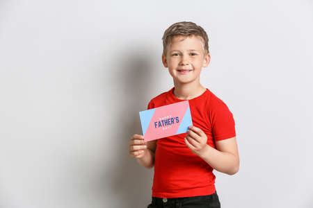 Little boy holding greeting card for Father's Day on light backgroundの写真素材