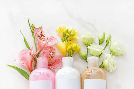 Bottles of shampoo and flowers on light backgroundの写真素材