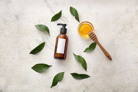 Bottle of shampoo, leaves and honey on light backgroundの写真素材
