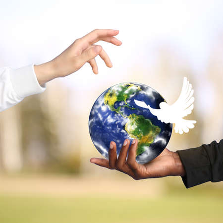 Hands of Caucasian woman and African-American man with model of Earth and dove on color background. International Day of Peaceの写真素材
