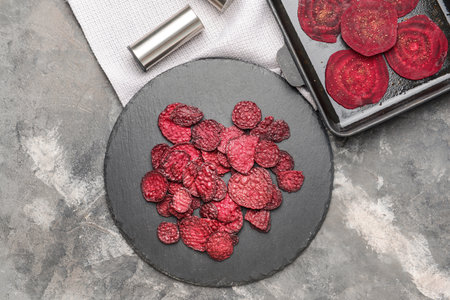 Slate plate with tasty beet chips on tableの写真素材