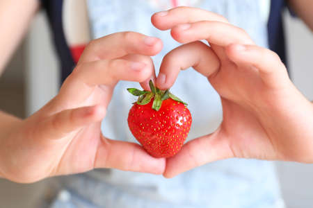 Woman with ripe red strawberry, closeupの写真素材