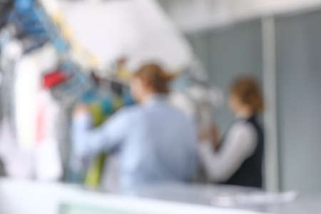 Workers of modern dry-cleaner's near rack with clothes, blurred viewの写真素材