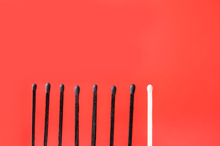 One unburnt match among burnt-out ones on color background. Concept of uniquenessの写真素材