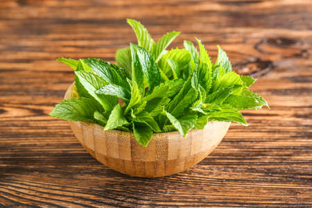 Bowl with fresh green mint on wooden tableの写真素材
