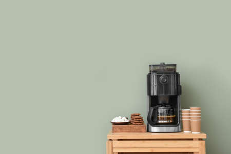 Modern coffee machine, cups, cookies and sugar on table against color backgroundの写真素材
