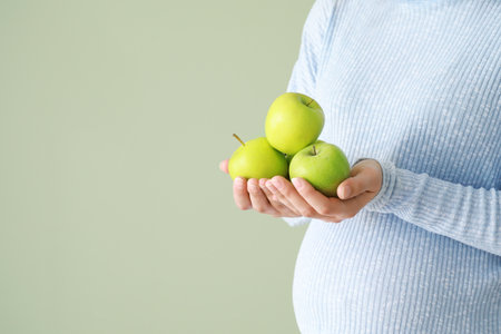 Beautiful pregnant woman with apples on color backgroundの写真素材