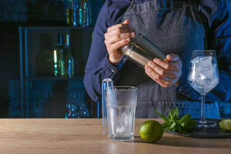 Barkeeper preparing cold cocktail at table in barの写真素材