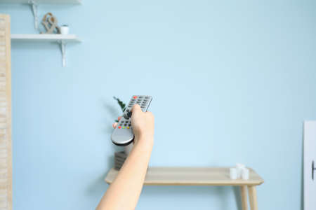 Young woman with TV remote control at homeの写真素材