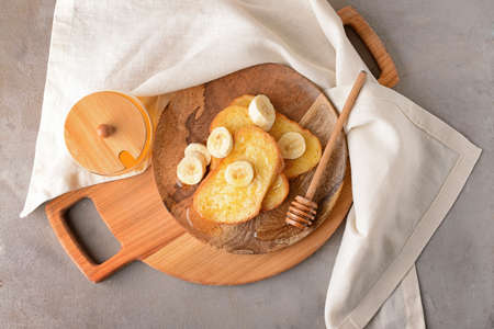 Plate with tasty French toasts, honey and banana on gray backgroundの写真素材