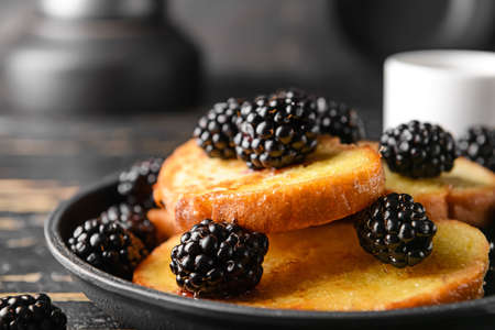 Tasty French toasts and blackberry in frying pan, closeup