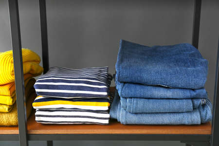 Stacked clothes on shelf against gray backgroundの写真素材