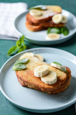 Plates with tasty French toasts and banana on tableの写真素材
