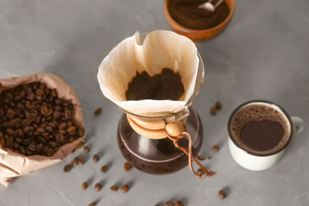 Tasty coffee in  cup on gray table