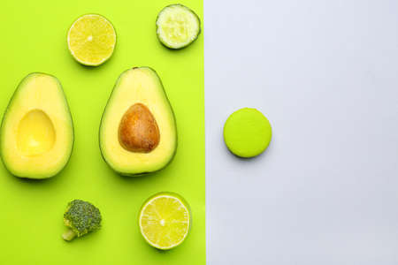 Fresh avocado, lime, cucumber, broccoli and macaron on color backgroundの写真素材