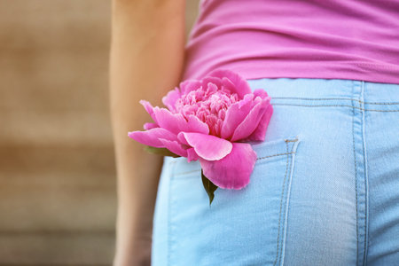 Woman with beautiful peony flower in pocket of her pants, closeupの写真素材