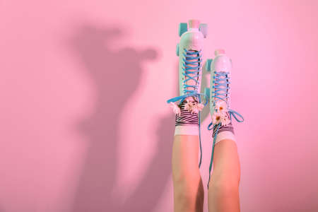 Legs of woman in vintage roller skates and with flowers on color backgroundの写真素材